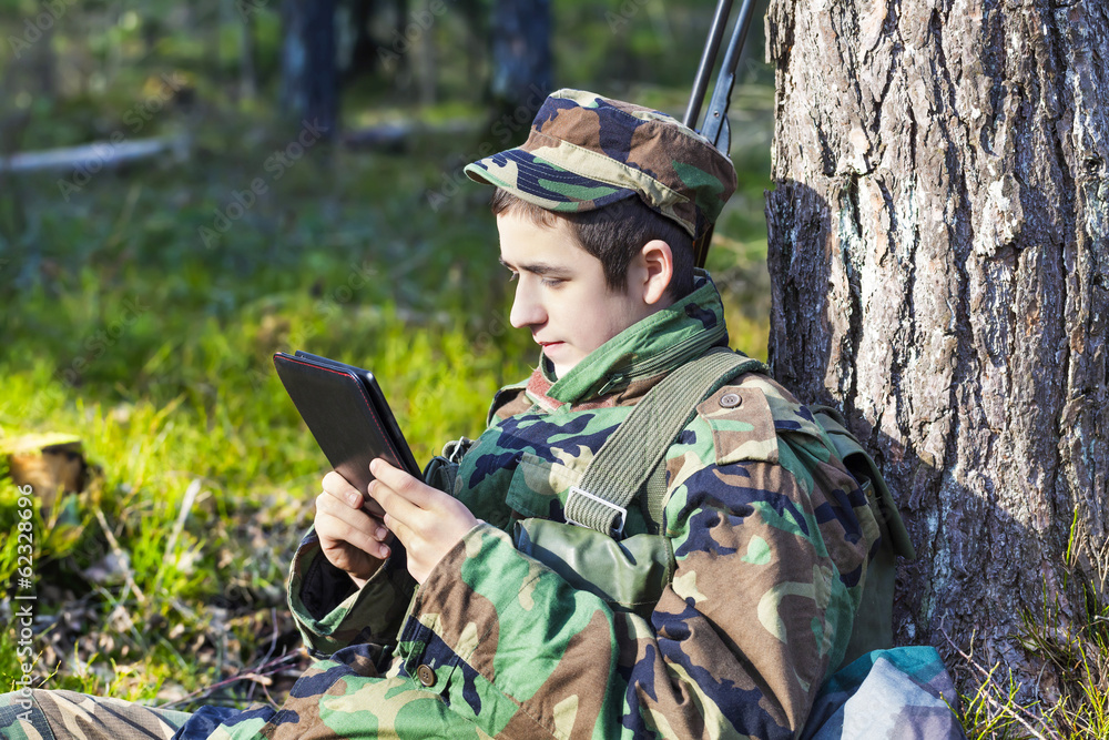 Recruit with tablet pc in forest near tree