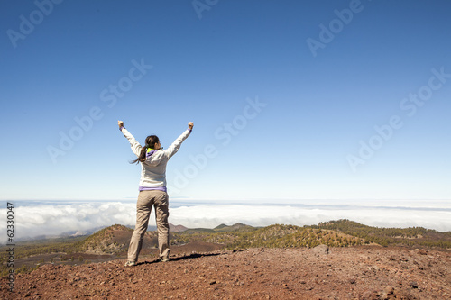 young woman on top of the moutain with the arms raised enjoying