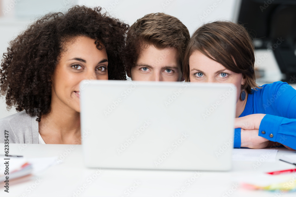 drei junge leute schauen über laptop drei junge leute schauen über laptop