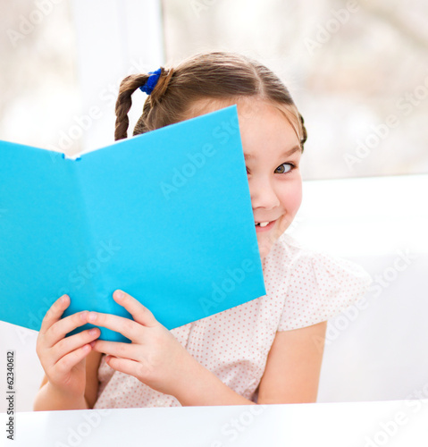 Little girl is reading a book
