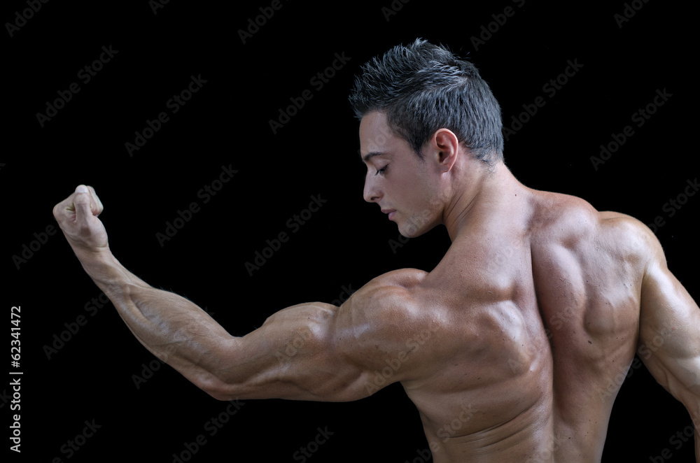 Muscular young bodybuilder's back. Looking at bicep