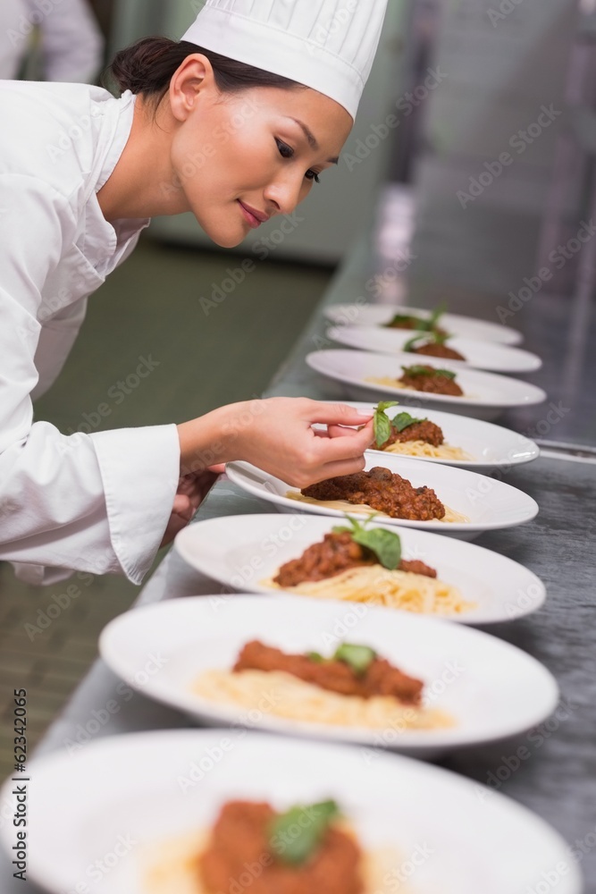 Happy chef putting basil leaf on spaghetti dish Happy chef putting basil leaf on spaghetti dish