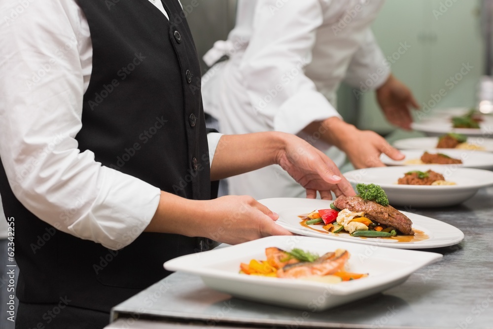 Waitress picking up steak dinner and salmon dinner Waitress picking up steak dinner and salmon dinner