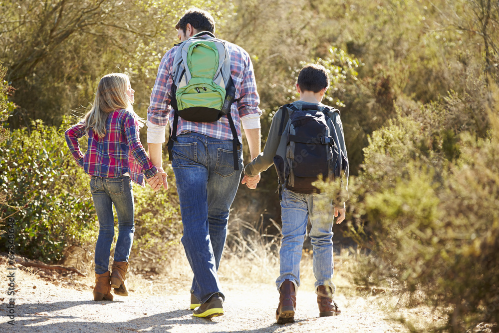 Rear View Of Father And Children Hiking In Countryside Rear View Of Father And Children Hiking In Countryside