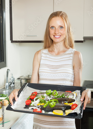Smiling housewife cooking fish