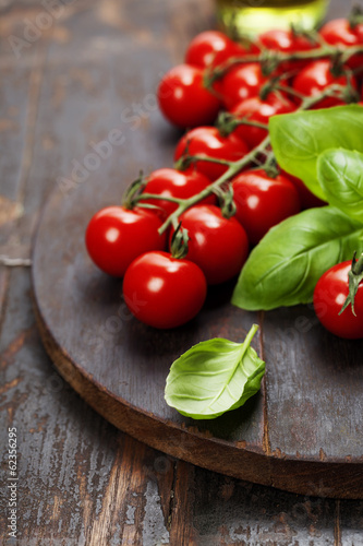 Tomatoes with basil on wooden table background