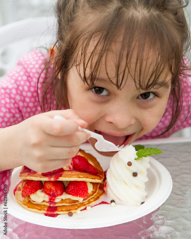 Young gril eating delicious strawberry waffle and ice cream Young gril eating delicious strawberry waffle and ice cream