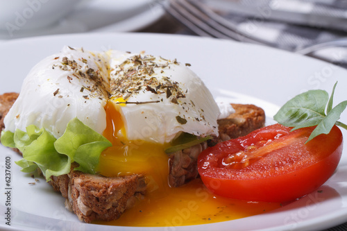 sandwich with salad, open poached egg on a white plate