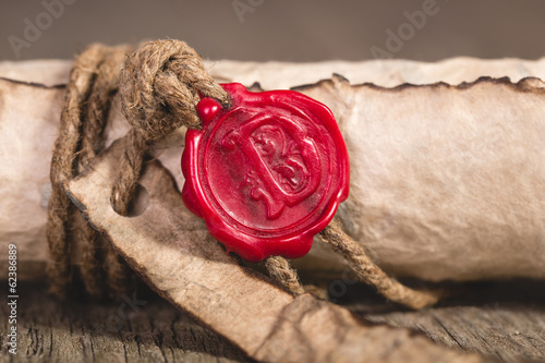 Old scroll paper on wooden background. Close up of wax seal.