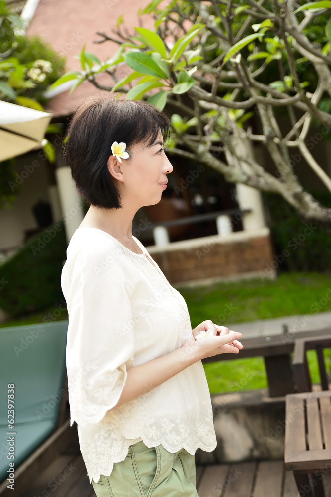 Naklejka premium Asian woman enjoying spring flowers in the garden