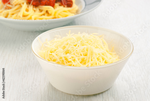 bowl of grated cheese to the bottom plate of spaghetti