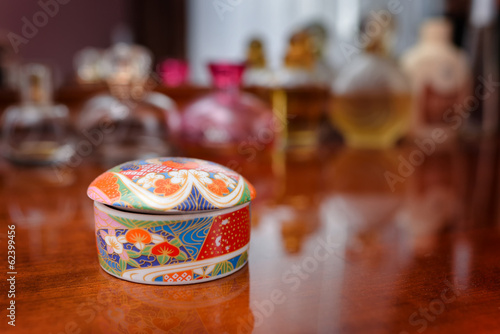 Ceramic jewelry box with some perfume in the background