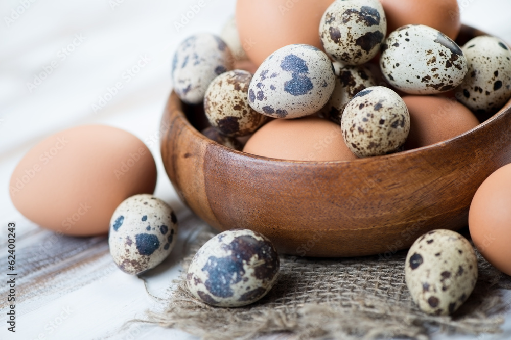 Obraz premium Wooden bowl with raw chicken and quail eggs, close-up