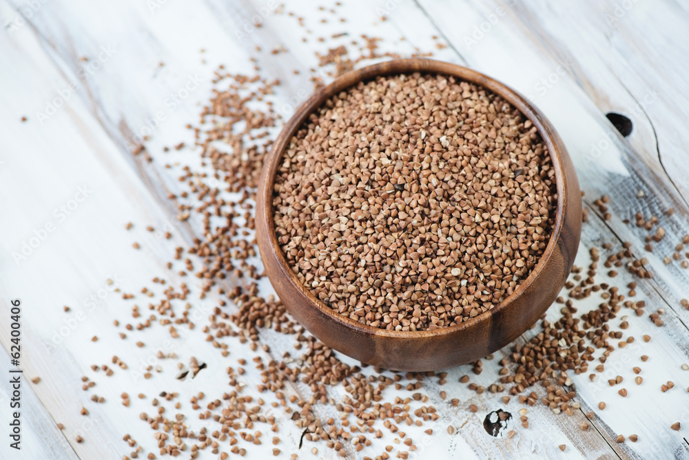 Raw buckwheat kernels in a wooden bowl, above view Raw buckwheat kernels in a wooden bowl, above view
