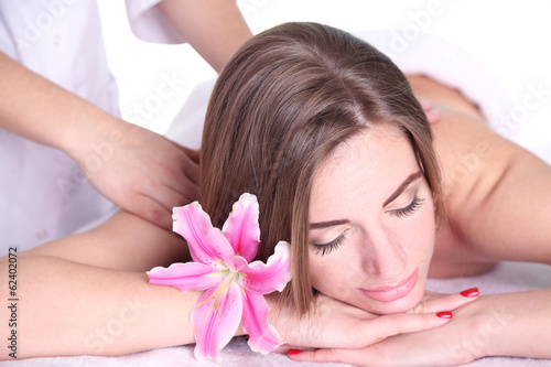 Beautiful young woman having back massage in spa salon
