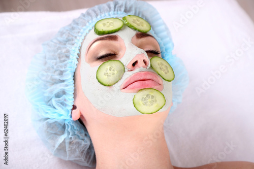 Young woman with clay facial mask in spa salon