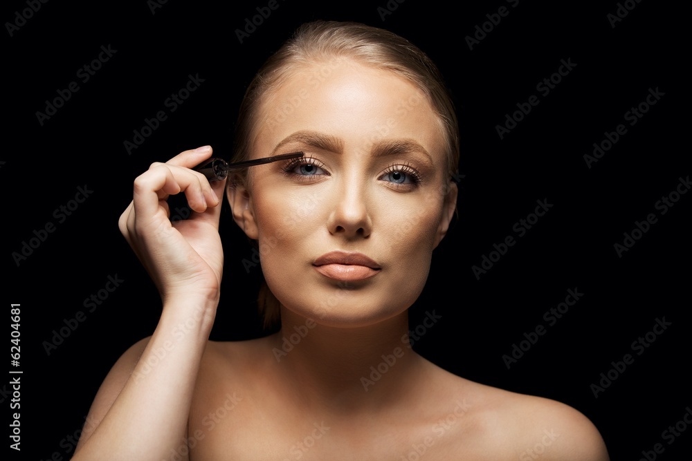 Attractive woman putting mascara on her eyelashes