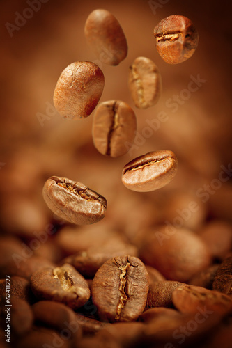 Fragrant fried coffee beans with focus on one are falling