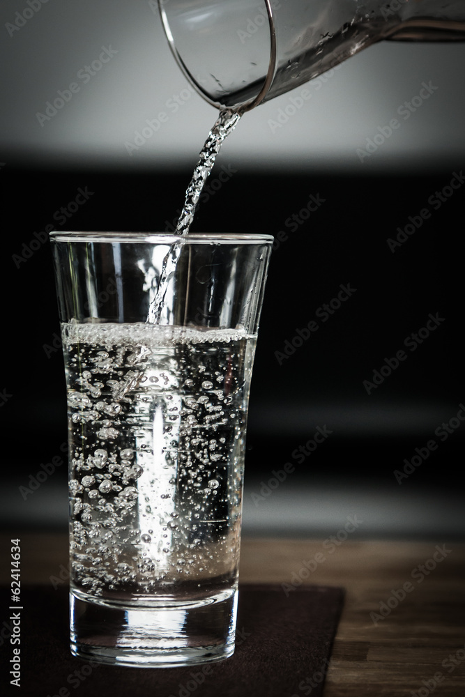 pouring some fresh clean water into glass with jug pouring some fresh clean water into glass with jug