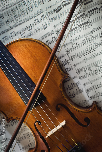 Wertvolle alte Geige mit Bogen liegt auf einem Notenblatt