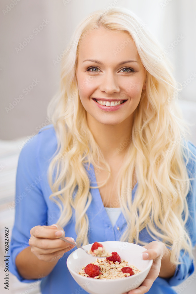 smiling woman with bowl of muesli having breakfast smiling woman with bowl of muesli having breakfast