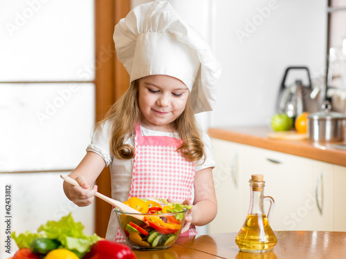 kid making salad at kitchen