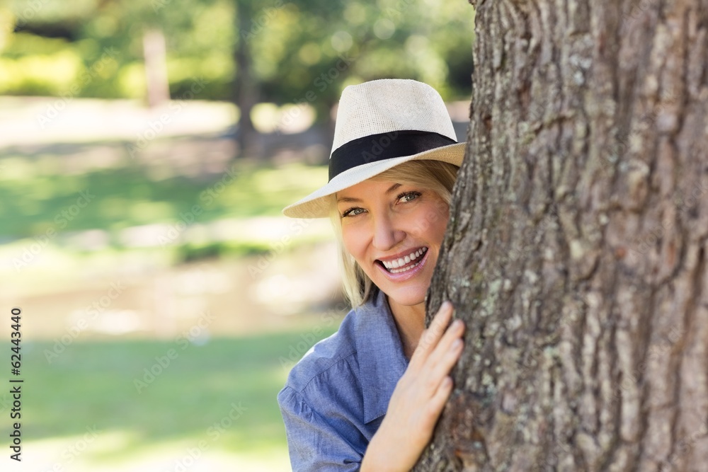 Woman hiding behind tree trunk