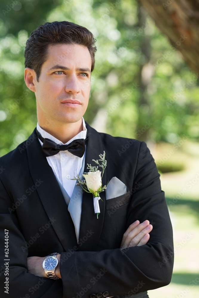 Thoughtful groom with arms crossed in garden Thoughtful groom with arms crossed in garden