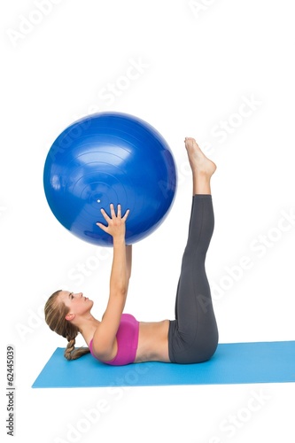 Side view of a fit woman exercising with fitness ball
