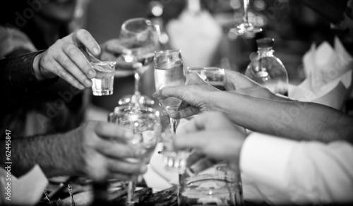 photo of hands clinking glasses with vodka at party