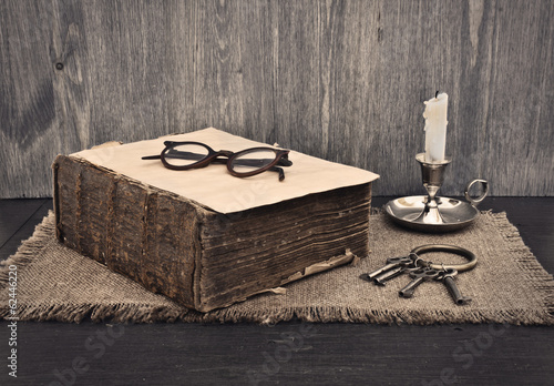old book, glasses and a bunch of keys on wooden background