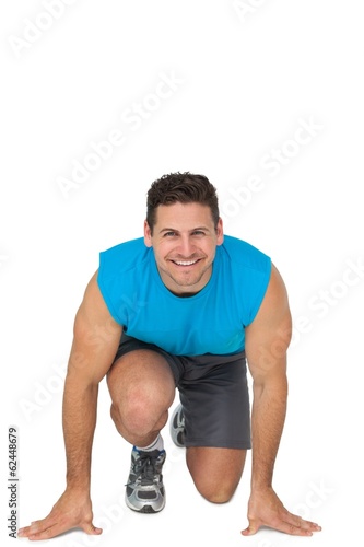 Portrait of a young sporty smiling man in running stance