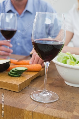 Mid section of couple with wine glasses and vegetables