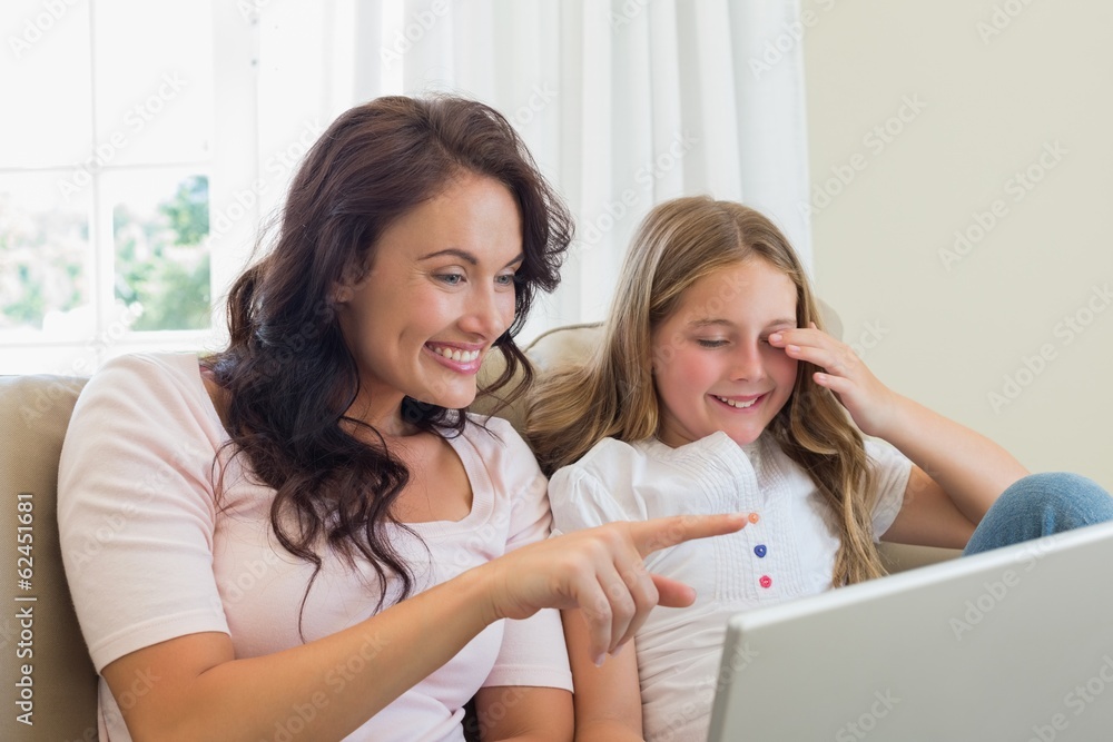 Smiling mother and daughter using laptop on sofa Smiling mother and daughter using laptop on sofa