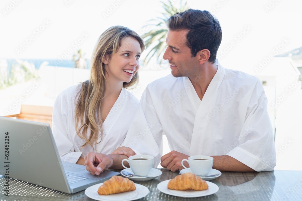 Couple using laptop on breakfast table Couple using laptop on breakfast table