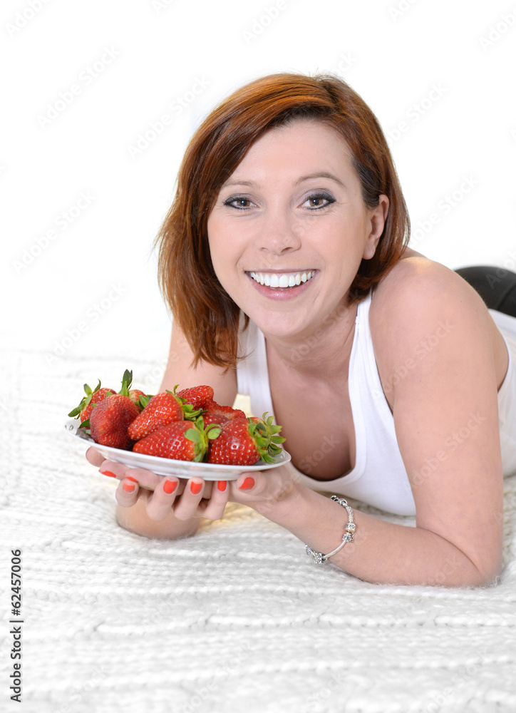 Young Attractive woman eating a bowl of strawberries in bed Young Attractive woman eating a bowl of strawberries in bed