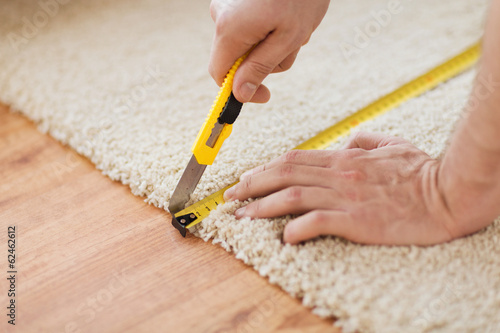 Obraz na plátně close up of male hands cutting carpet