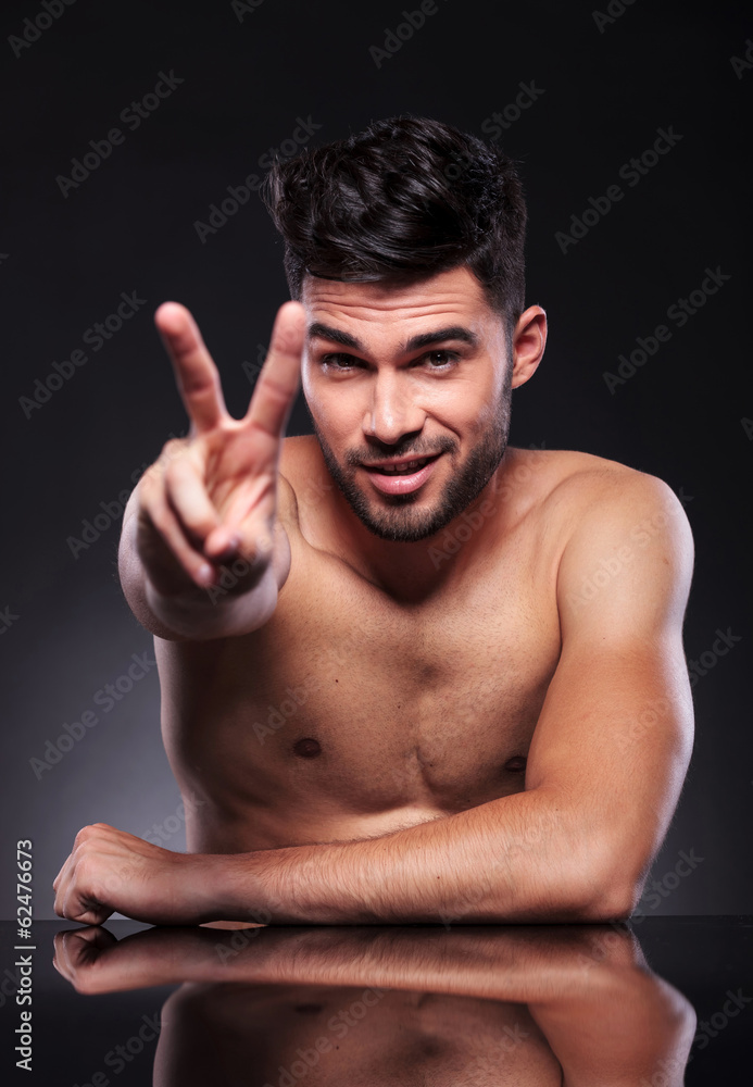 naked young man shows victory naked young man shows victory