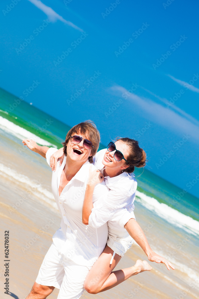 happy young couple in white clothes and sunglasses smiling on