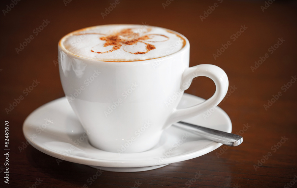 Fototapeta premium One white cup of cappuccino stands on dark wooden table