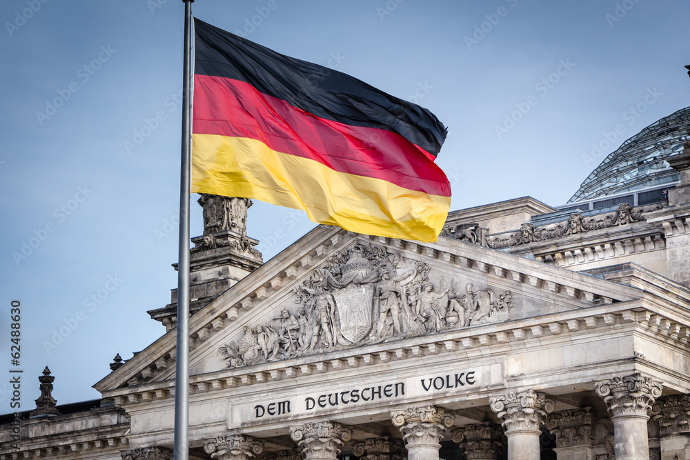 Naklejka premium Niemiecka flaga przed Reichstagiem - niemieckim parlamentem