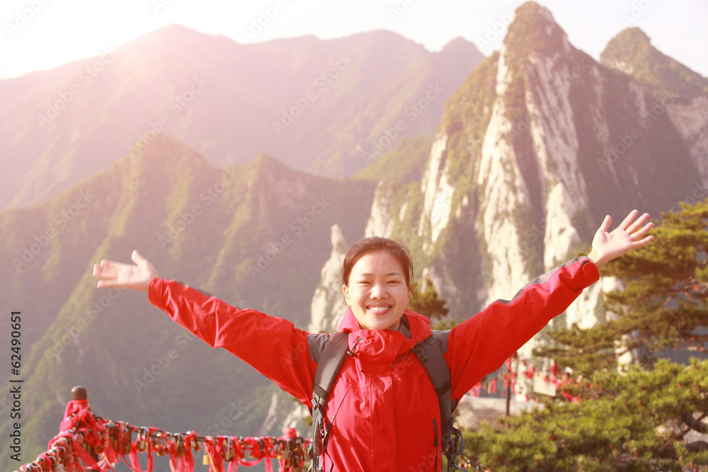 cheering woman hiker open arms at peak of mountain huashan