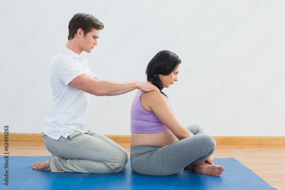 Masseur rubbing pregnant womans shoulders Masseur rubbing pregnant womans shoulders