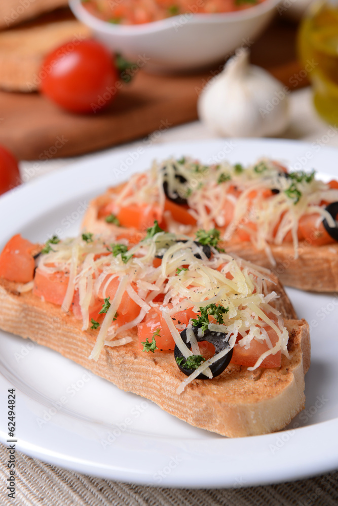 Delicious bruschetta with tomatoes on plate on table close-up