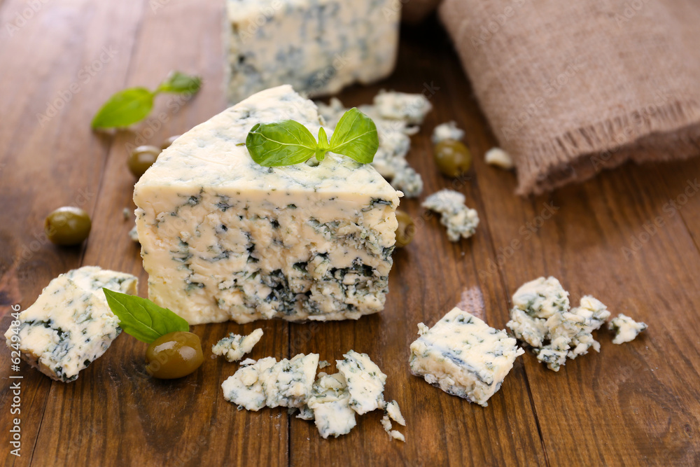 Tasty blue cheese with olives and basil, on wooden table Tasty blue cheese with olives and basil, on wooden table