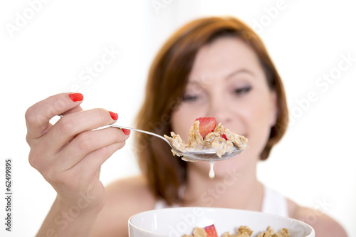 close up of spoon of woman eating cereal with strawberries