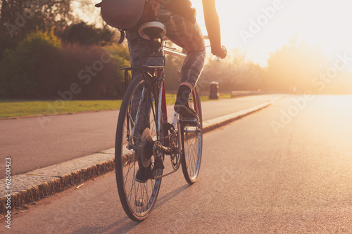 Fotografie, Obraz Young woman cycling in the park at sunset