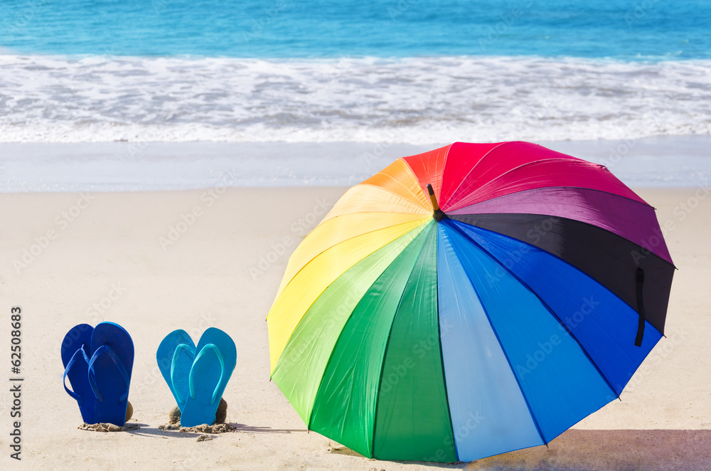 Summer background with rainbow umbrella and flip flops
