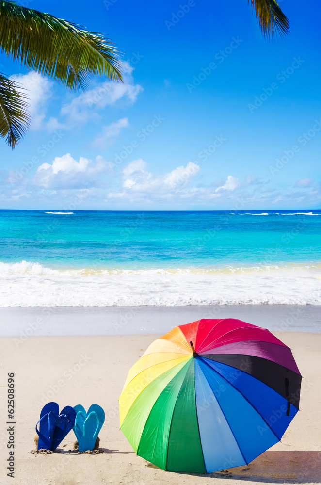 Summer background with rainbow umbrella and flip flops