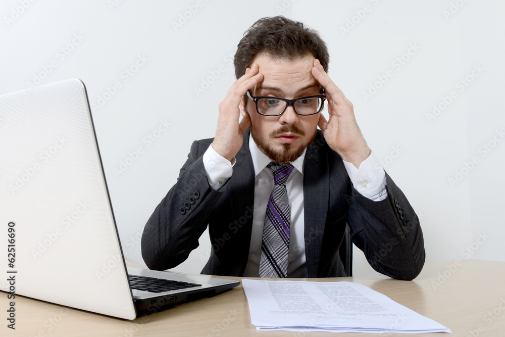 Worried young businessman with laptop and documents Worried young businessman with laptop and documents
